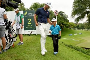 Adam Scott presents Braydon Lee with a signed glove. Picture by Khalid Redza/Lagardère Sports.